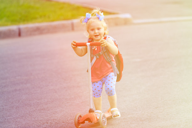 可爱的小女孩骑着滑板车在城里图片下载