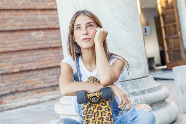 漂亮的年轻女人，带着他的斑点滑板图片下载