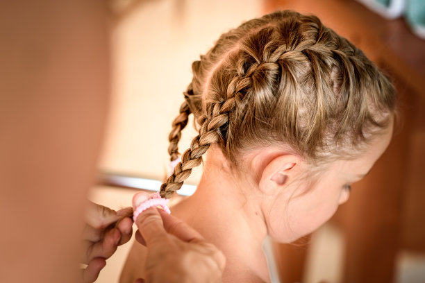 妈妈正在给小女儿的头上编辫子。图片下载