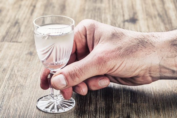 酗酒。男人手酒精和喝的蒸馏物图片下载