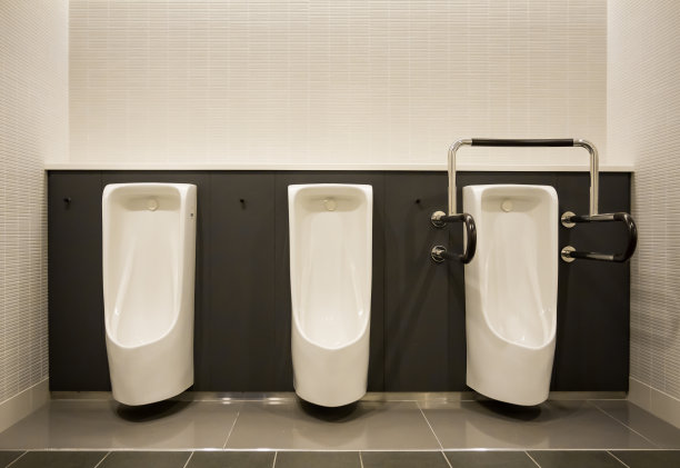 男厕所的白色小便池，墙上贴着灰色瓷砖图片下载