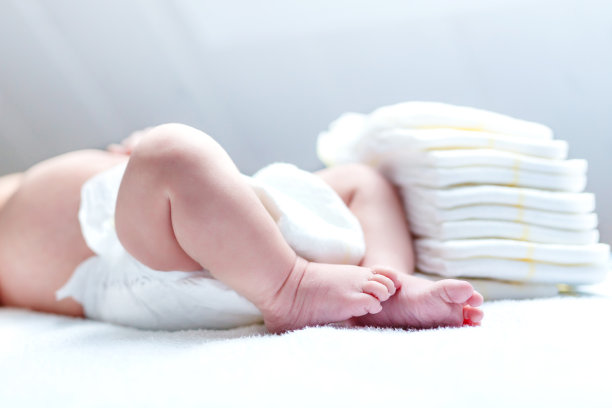 新生婴儿在换尿布台上，脚边放着尿布素材图片