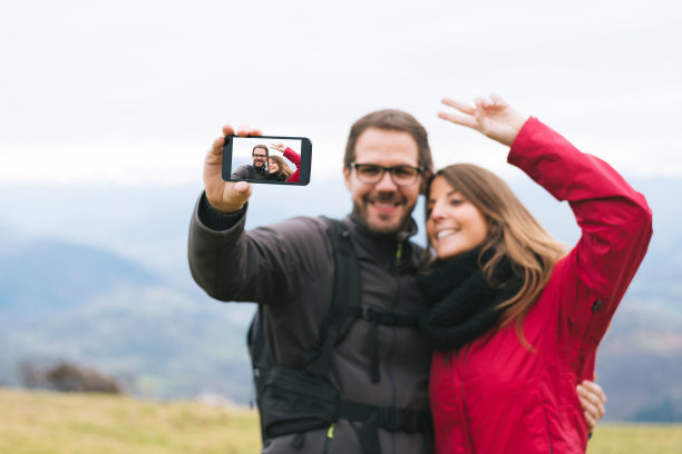 相爱的情侣在徒步旅行时自拍做和平标志图片下载