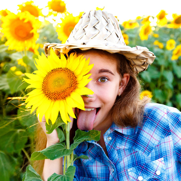 快乐的女孩，带着向日葵，柳条帽子，露出舌头图片下载