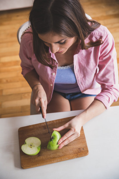 年轻女子切苹果。从上面图片。图片下载
