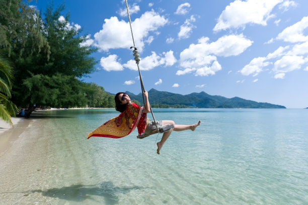 美丽的女孩在海边玩秋千的时候泼水图片下载