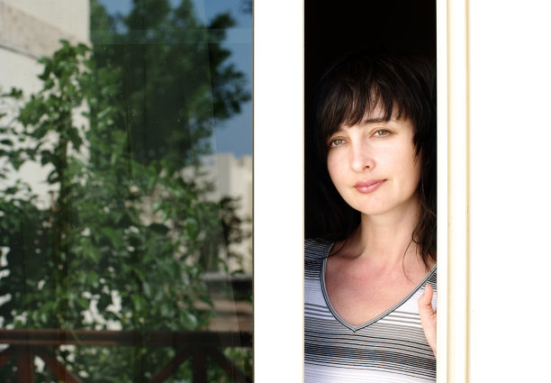 漂亮的黑发女人从阳台往外看图片下载