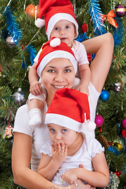 快乐的妈妈和她戴着圣诞帽的小女儿们图片下载
