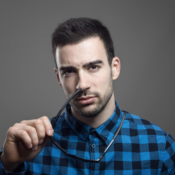 这是一幅怀疑的男人的肖像，他摘下墨镜看着相机图片下载