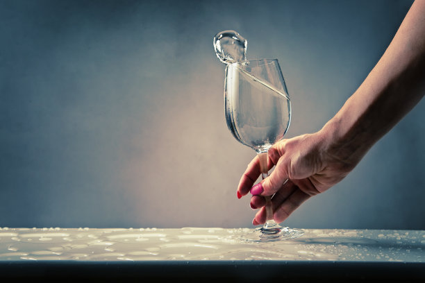 女士一手捧着盛满水的酒杯泼洒图片下载