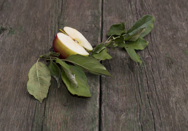 切好的带叶子的苹果放在一张旧木桌上图片下载