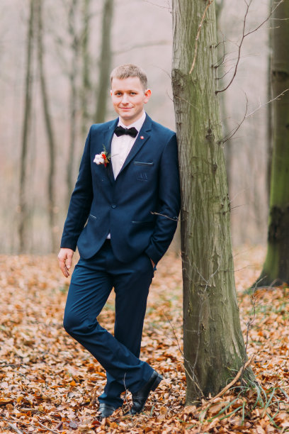 英俊自信的新郎在树旁摆姿势图片下载