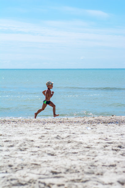小男孩在夏天的海滩上跑步图片下载