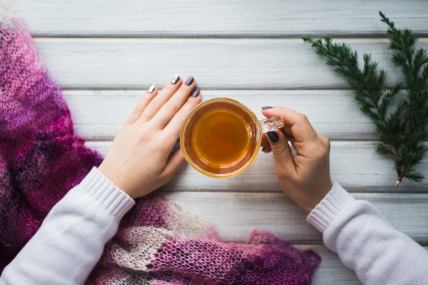 拿着一杯茶的女人在木桌上方。图片下载