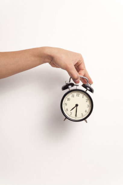 手持一个闹钟在白色的背景图片下载