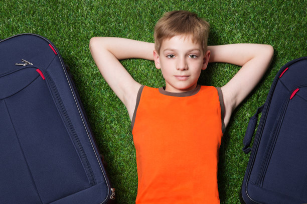 男孩和箱子躺在绿色的草地上图片下载