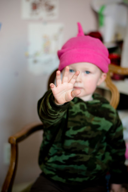 戴着粉红色帽子的男孩把手举起来停在客厅里图片下载