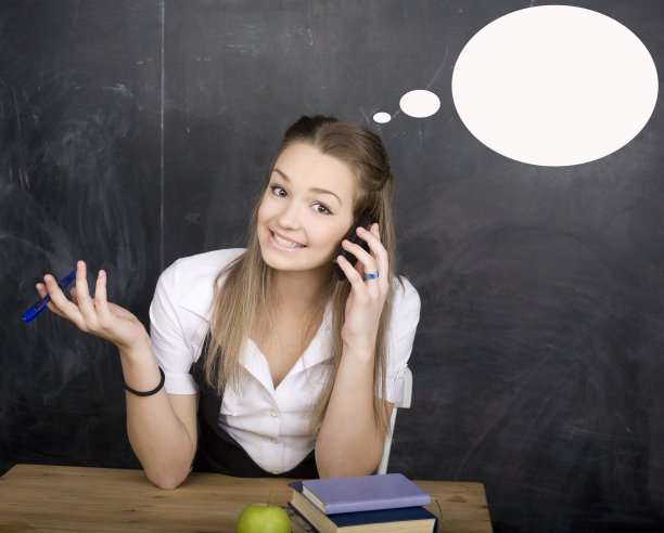 年轻漂亮的女学生在教室的黑板上做作业图片下载