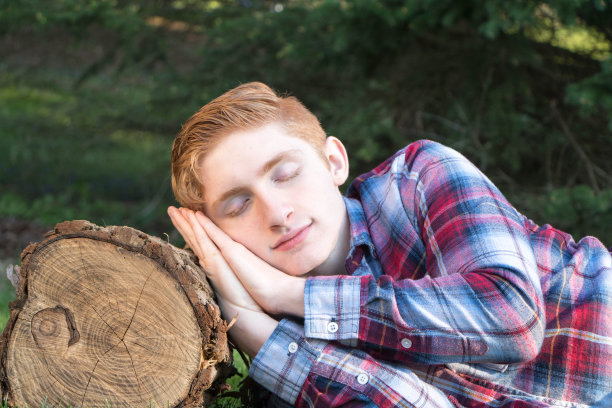 在木头上睡觉的青少年图片下载