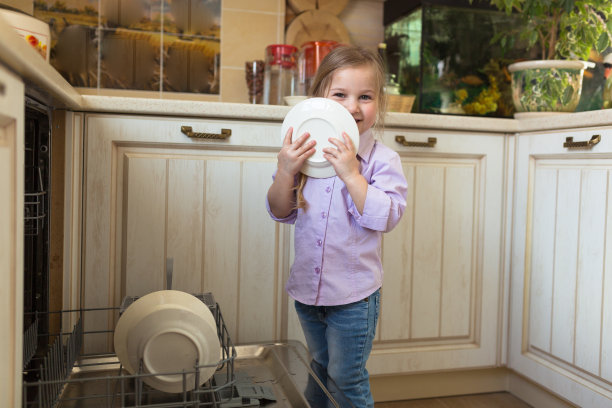 微笑的白人女孩在厨房帮忙把盘子拿出来图片下载