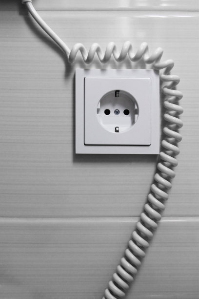电源插座和盘式电缆/电线可能属于贴在瓷砖墙上的吹风机图片下载