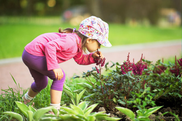 美丽的小女孩在花园里闻花图片下载