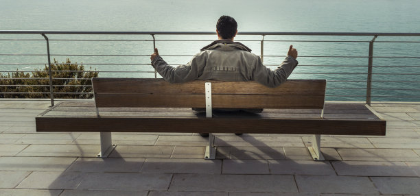 坐在海边长凳上的人的后视图图片下载