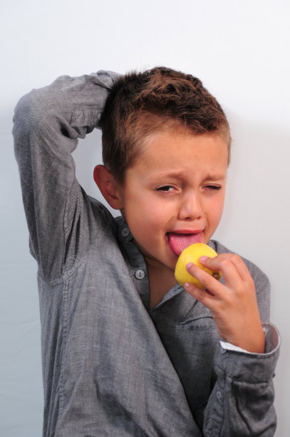 男孩一边吃着柠檬一边做鬼脸图片下载