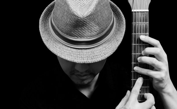 亚洲英俊的吉他手与帽子在吉他上摆姿势图片下载