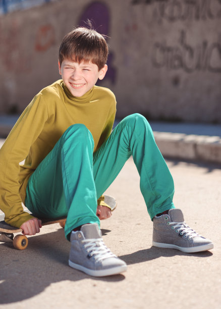 笑着坐在滑板上的男孩图片下载