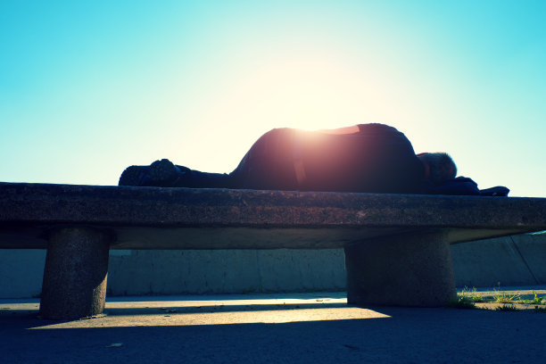 醉醺醺的成年人在公园的长椅上休息，强烈的阳光图片下载