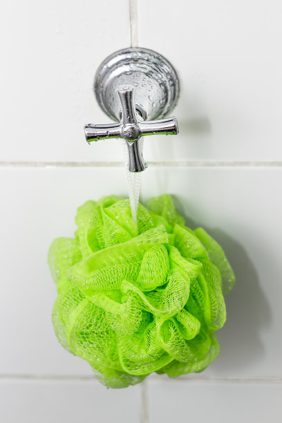 绿色海绵挂在水龙头上做浴室。图片下载