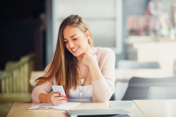 快乐的女人在咖啡馆使用智能手机图片下载