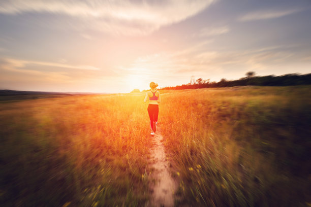 日落时分，一个年轻女子在乡间小路上奔跑图片下载
