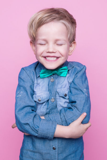 穿着蓝色衬衫，系着蝶形领带，面带微笑的年轻英俊的孩子图片下载