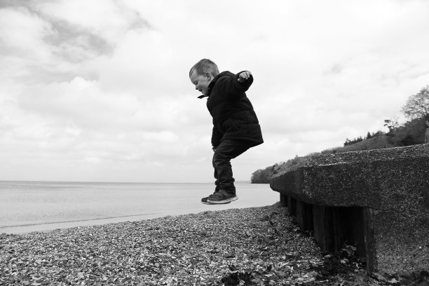 男孩从墙上跳到海滩上图片下载