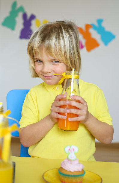 可爱的小男孩用吸管喝橘子汁图片下载