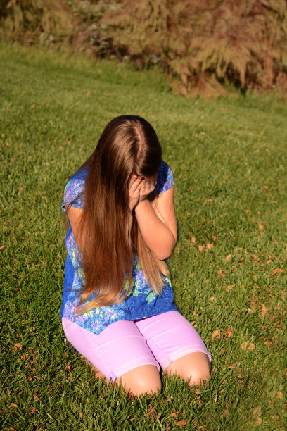 坐在草地上哭泣的女孩。图片下载