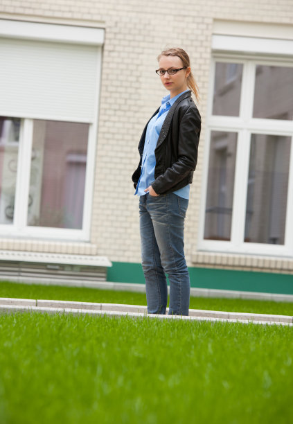 年轻女子站在砖墙建筑的背景图片下载