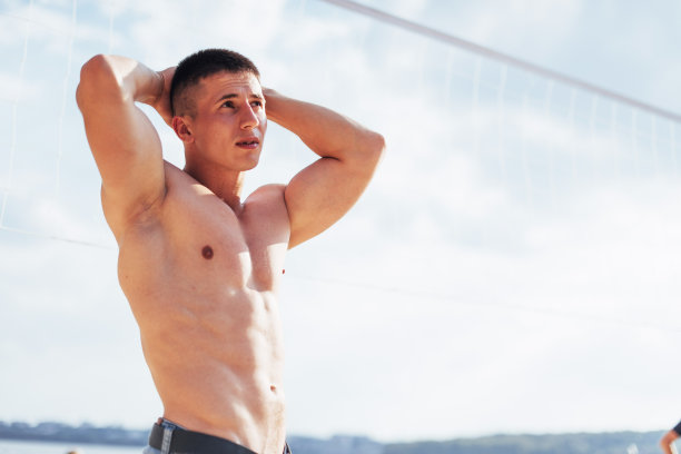 肌肉男模特与完美的身体姿势在蓝色牛仔裤图片下载