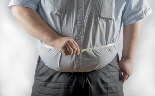 一个肥胖的男人在测量他的腰围图片下载