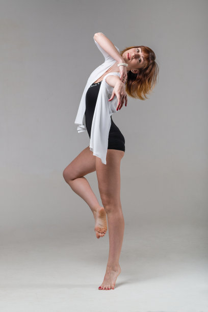 年轻的女芭蕾舞演员在灰色的背景上跳舞图片下载
