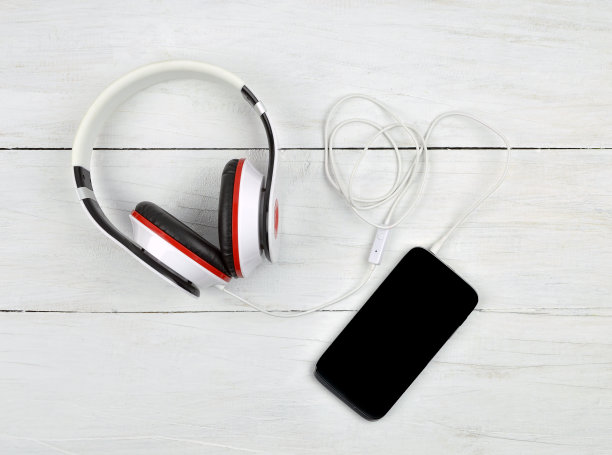 木制背景下的智能手机和耳机。放松。前视图。图片下载