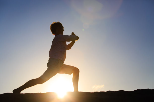 Ilhouette的年轻人做瑜伽在日落图片下载