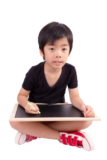 小男孩微笑着用粉笔在黑板上画图片下载