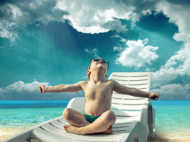 戴着墨镜的孩子在阳光下的水旁玩耍图片下载