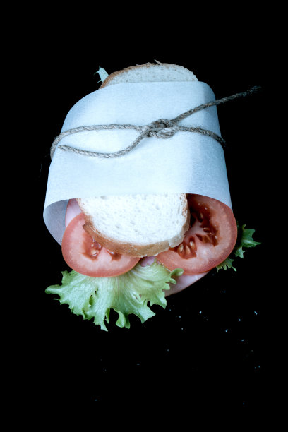 三明治与香肠包扎麻线在黑色的背景。与图片下载