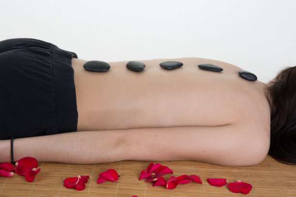 照片中的女人在温泉沙龙与热石头孤立图片下载