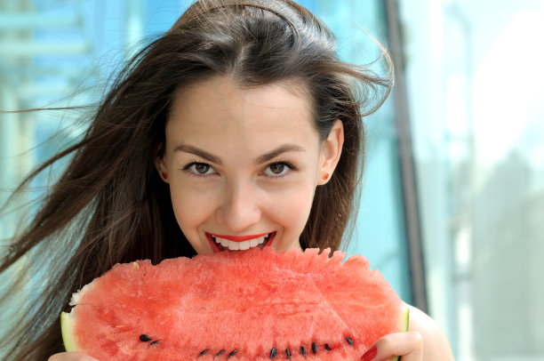 美丽的女孩在吃西瓜。图片下载