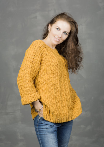 一个穿着黄色毛衣和牛仔裤的女人的肖像。图片下载